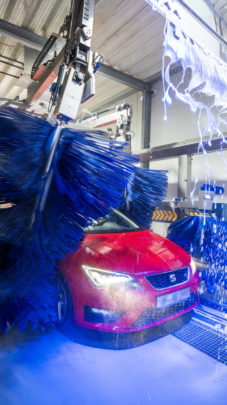 Rotes Fahrzeug zwischen den blauen Textilwalzen der Waschstraße